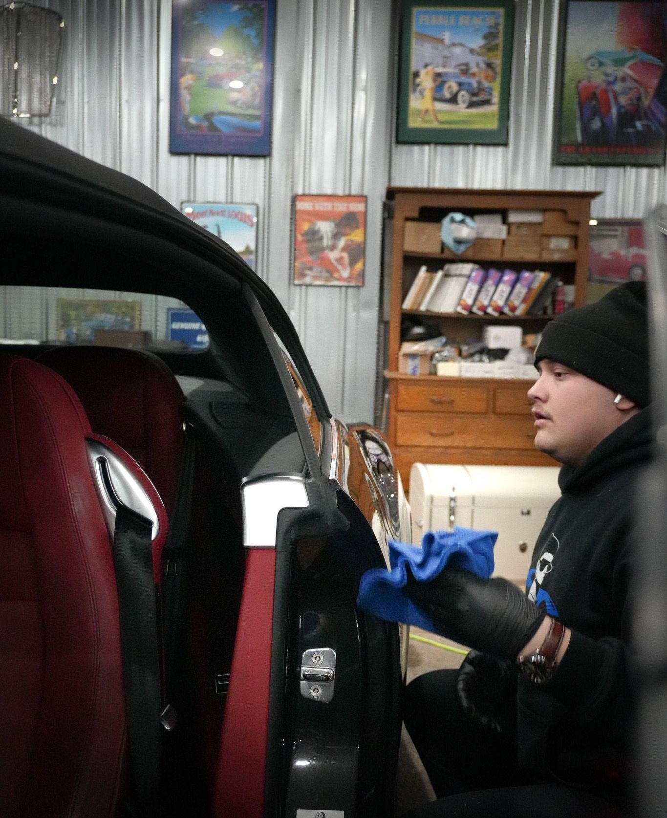 A man is cleaning a car door with a blue cloth