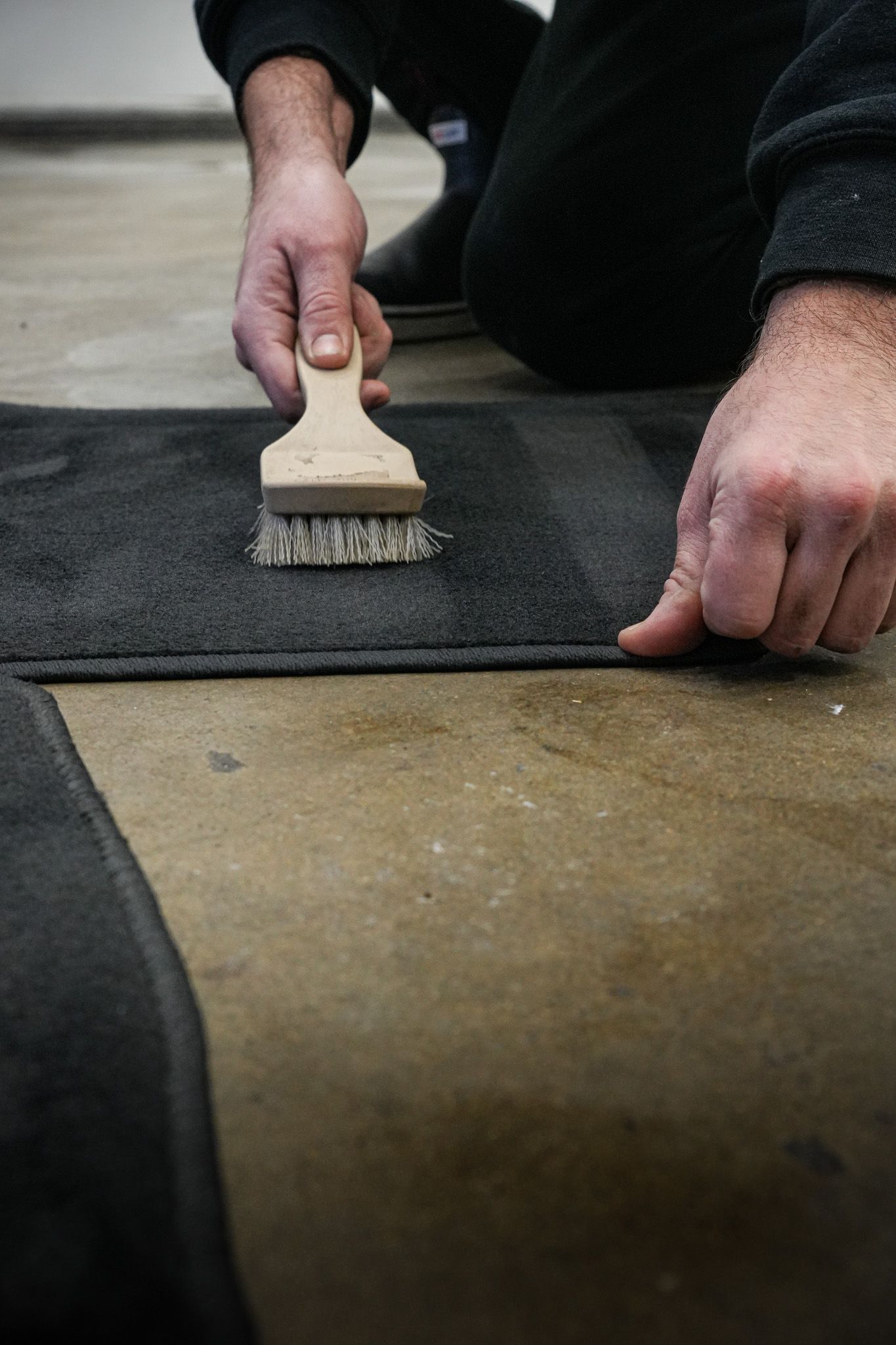 A person is cleaning a rug with a brush.