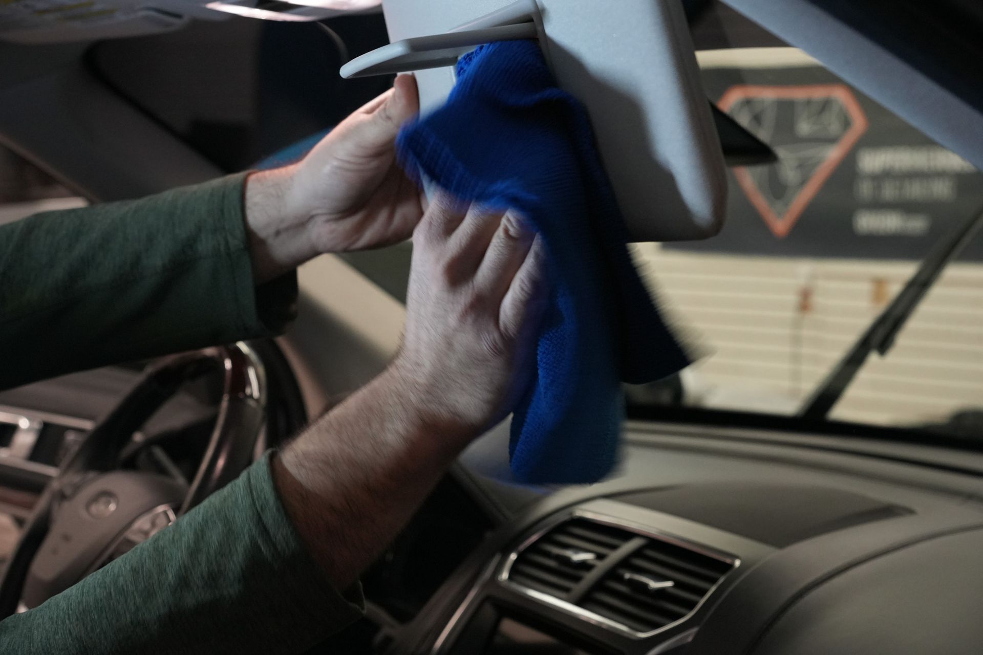 A person is cleaning the dashboard of a car with a blue cloth