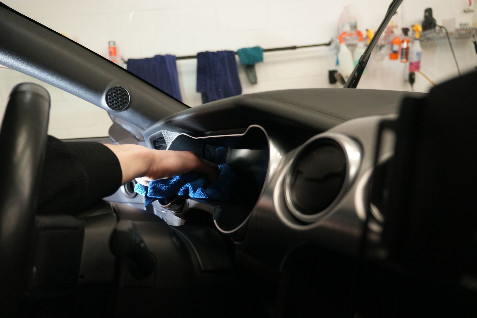 A person is cleaning the dashboard of a car with a cloth.