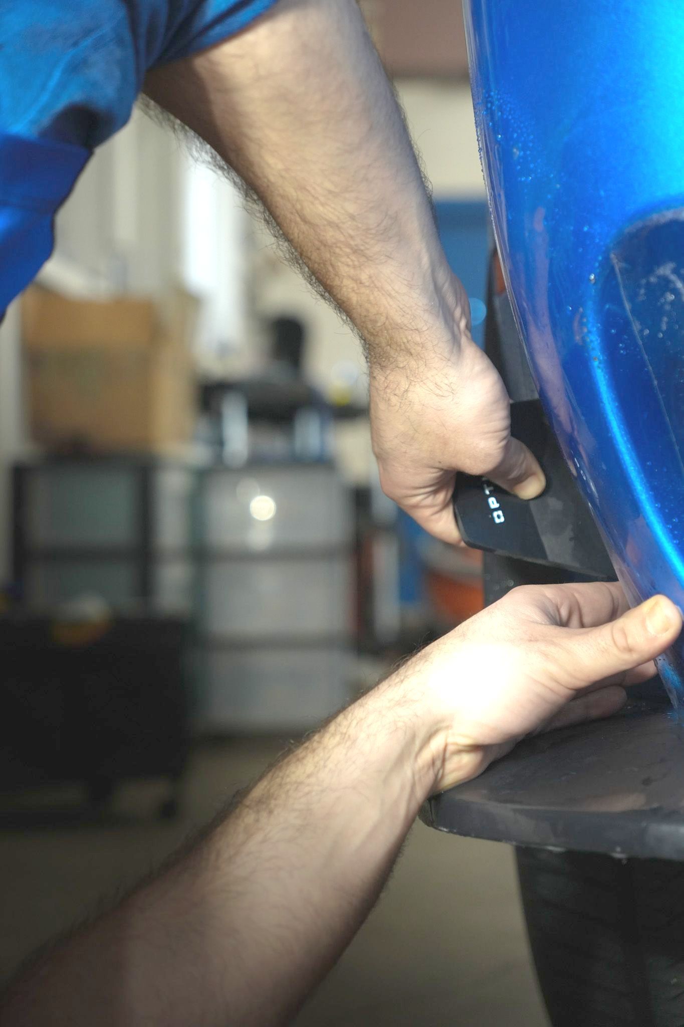 A man is working on a blue car in a garage.