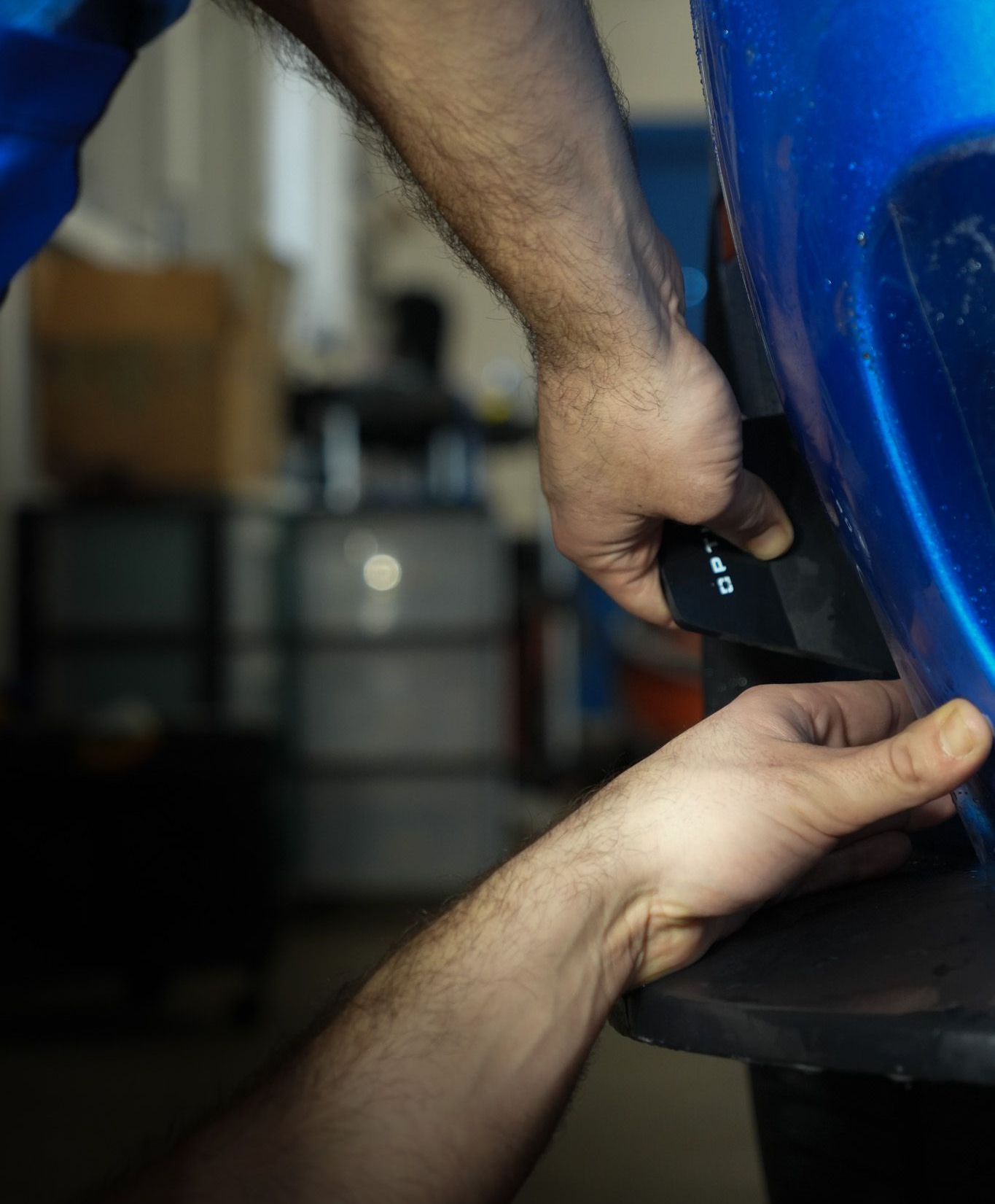 A man is working on a blue car in a garage.