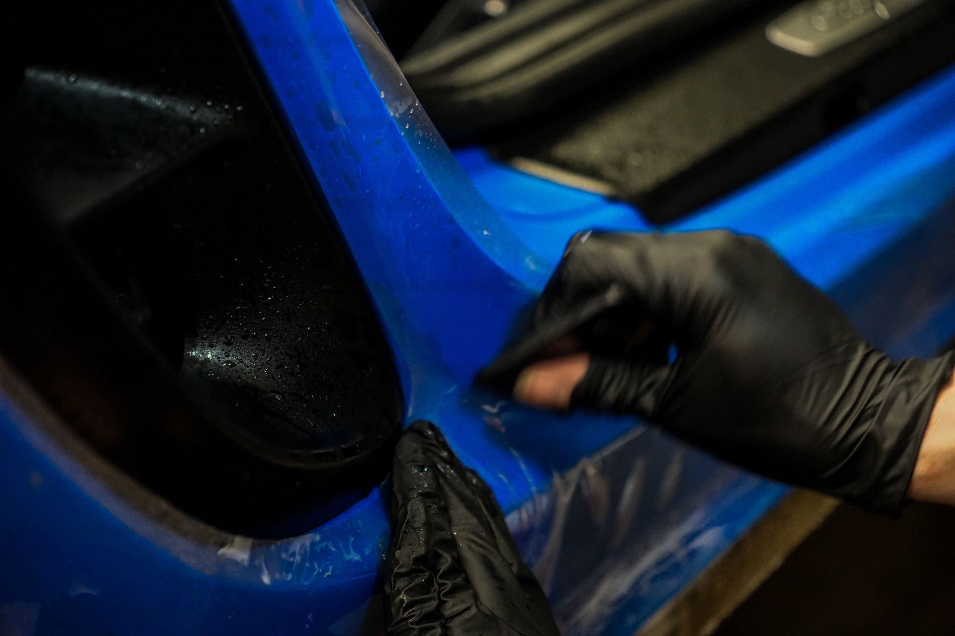 A woman is polishing a car with a machine in a garage.