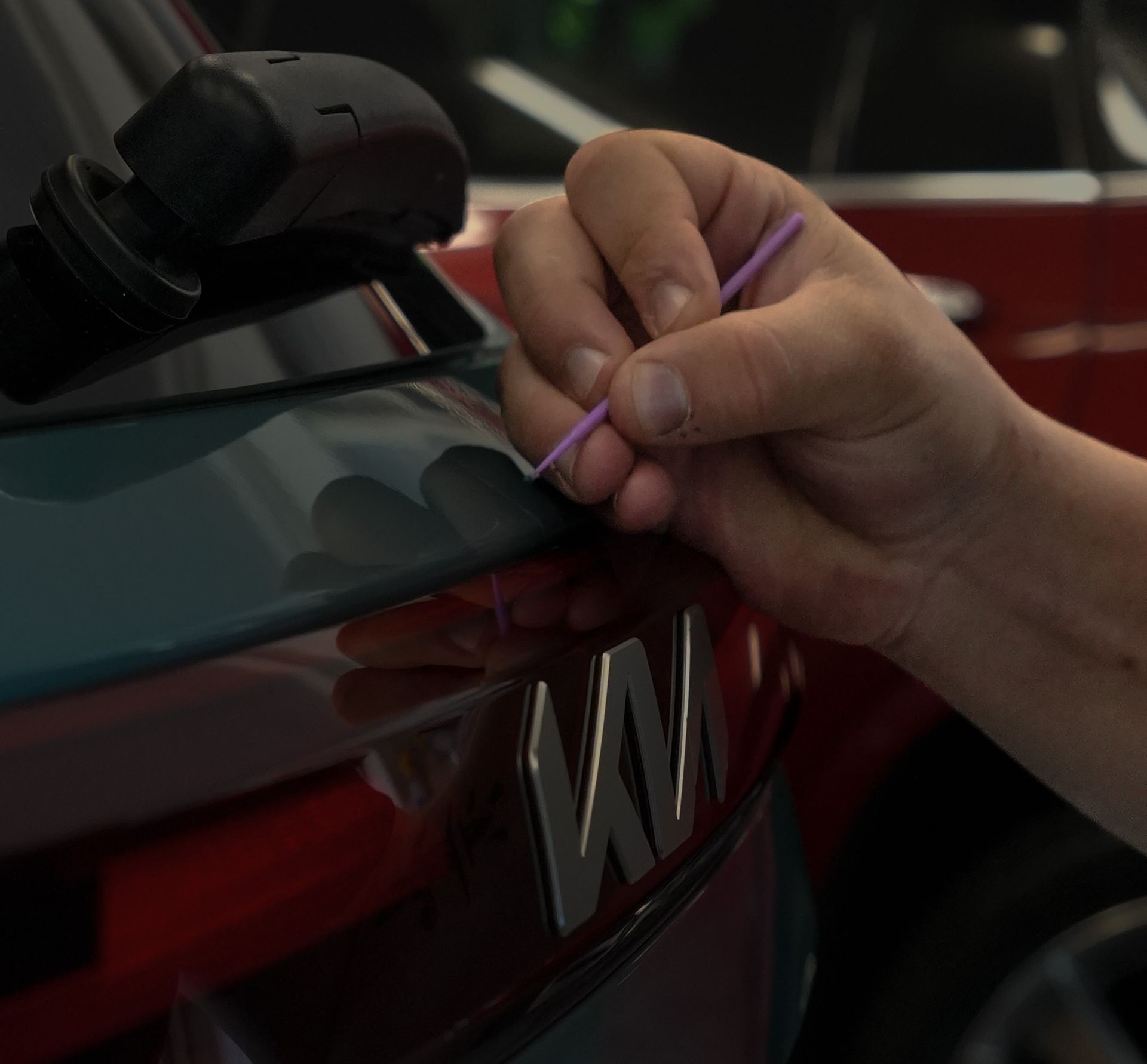 A person is scratching a car with a pen.