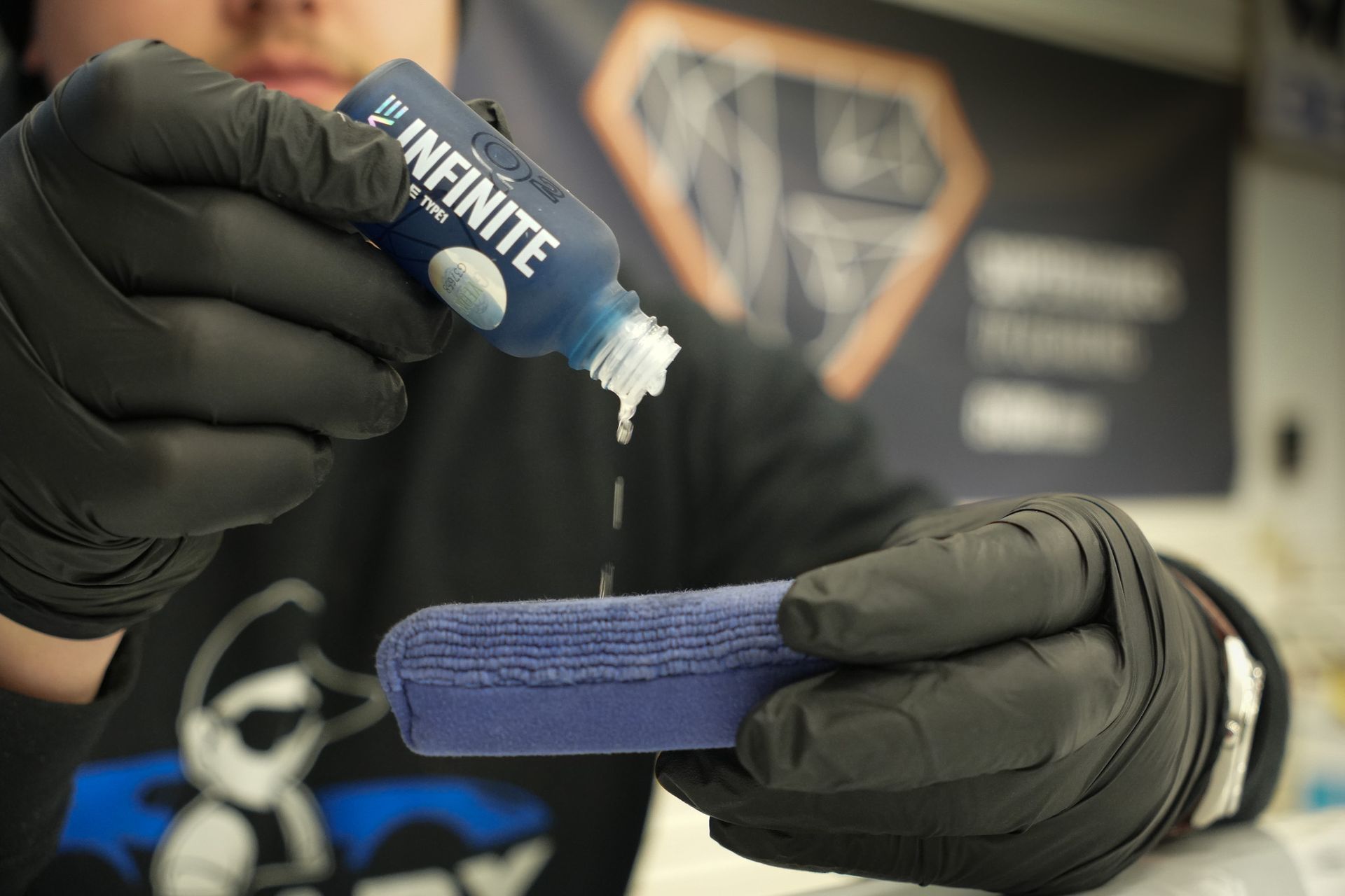 A person is holding a bottle of infinite and a cloth.