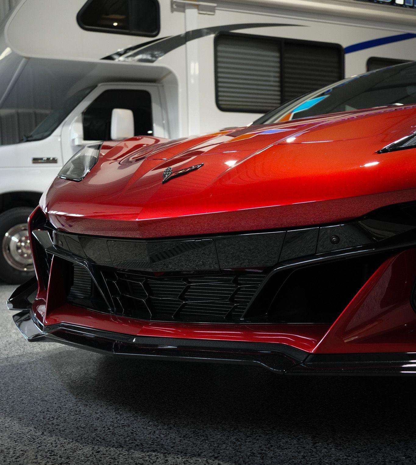 A red sports car is parked in a garage next to a rv