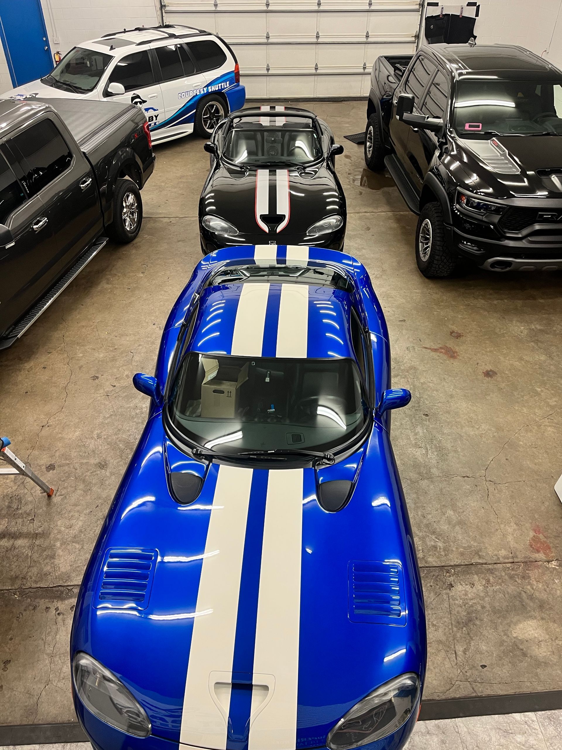 A man is working on a blue car in a garage.