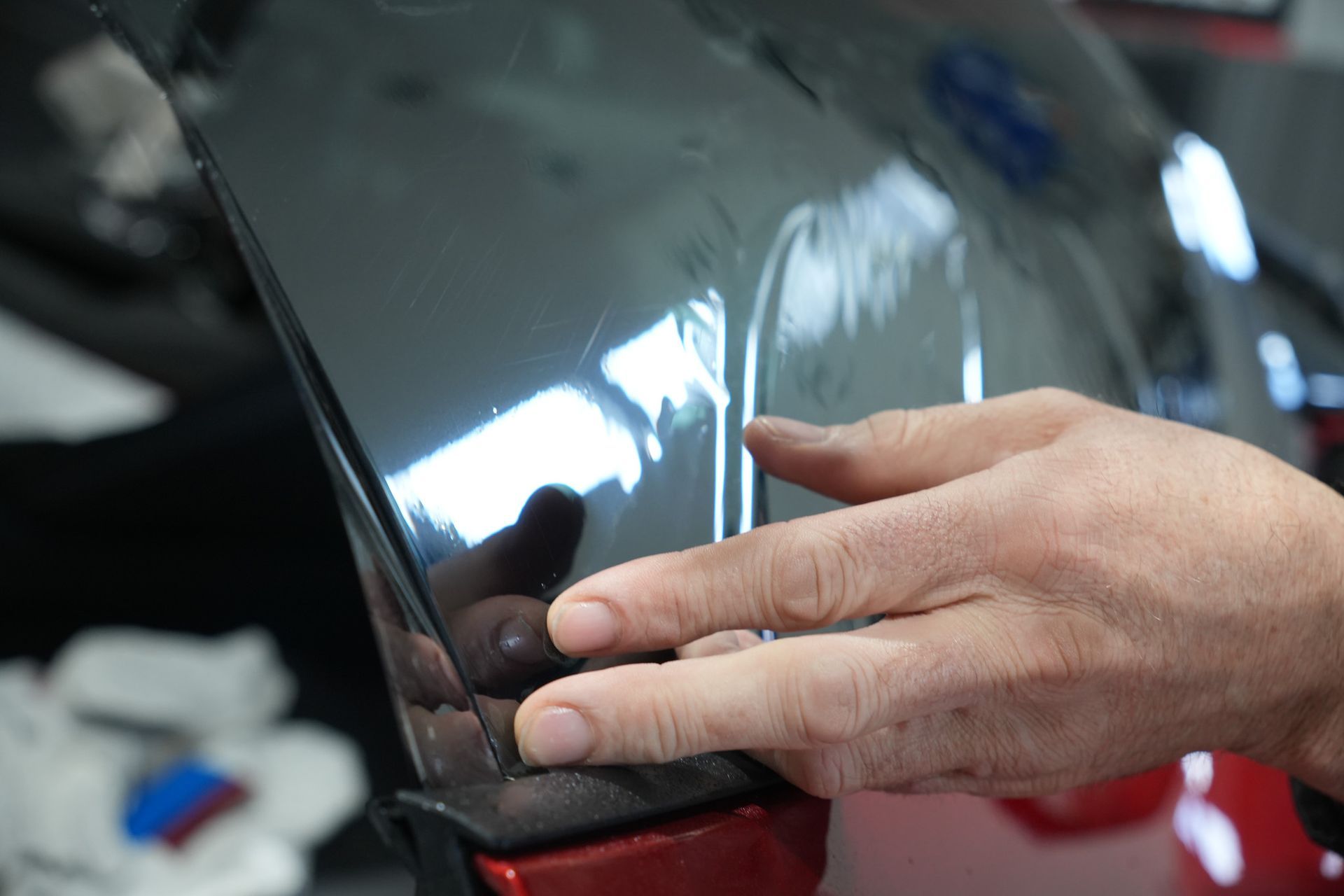 Applying window tint to red corvette