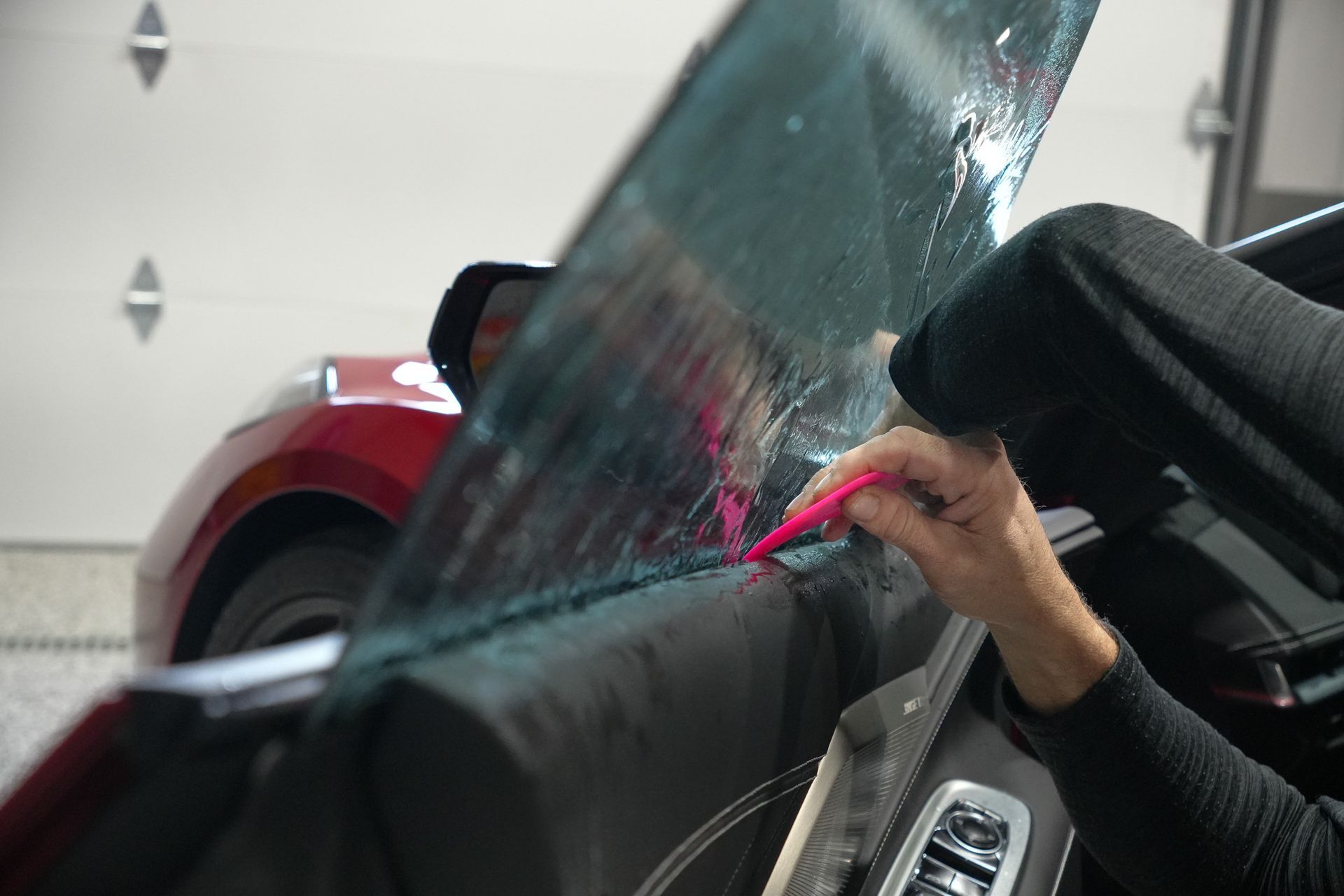 A person is applying window tinting to a car door.