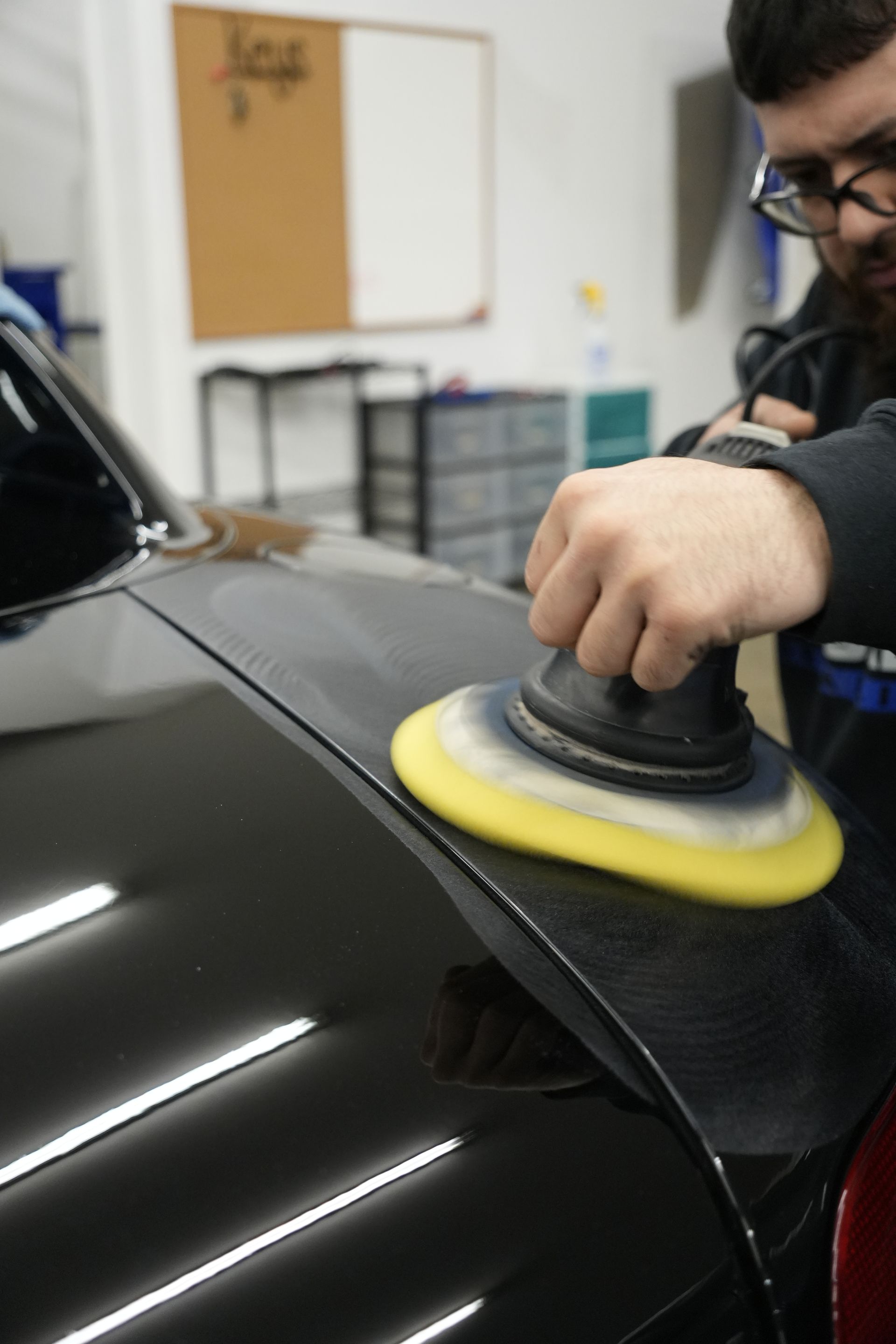A person is polishing a car with a machine.