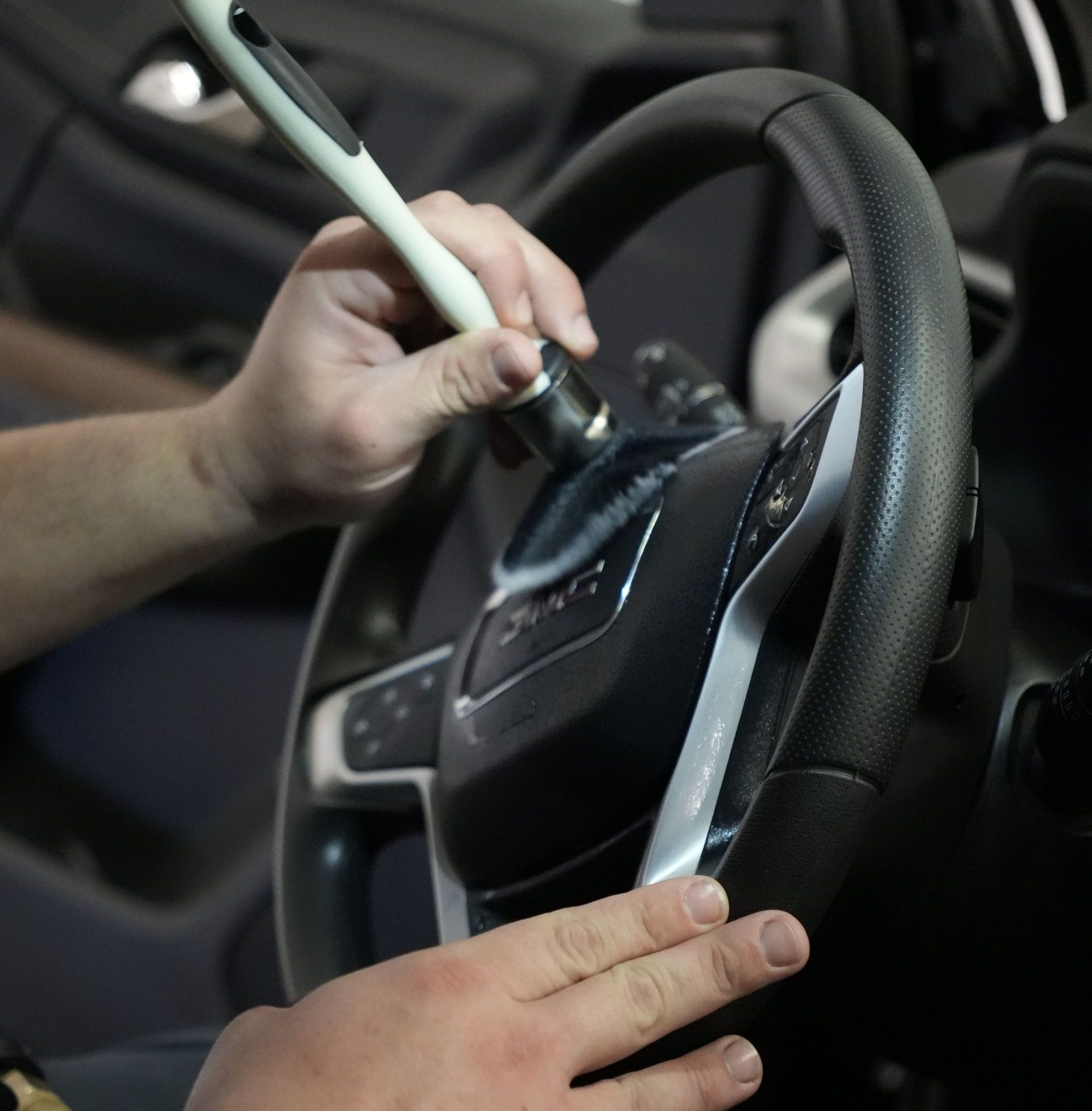 A man is cleaning the steering wheel of a car