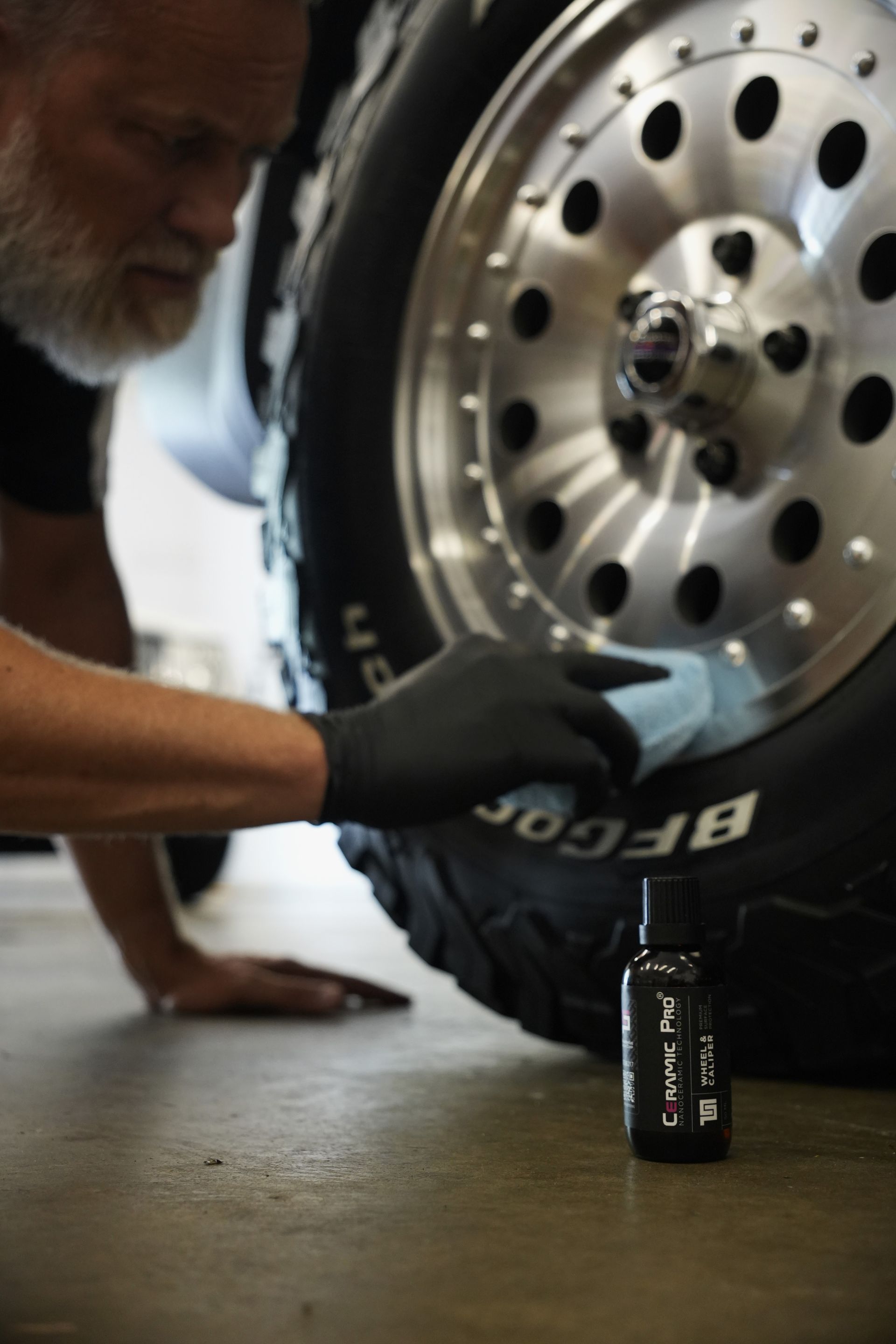 A man wearing black gloves is working on a tire