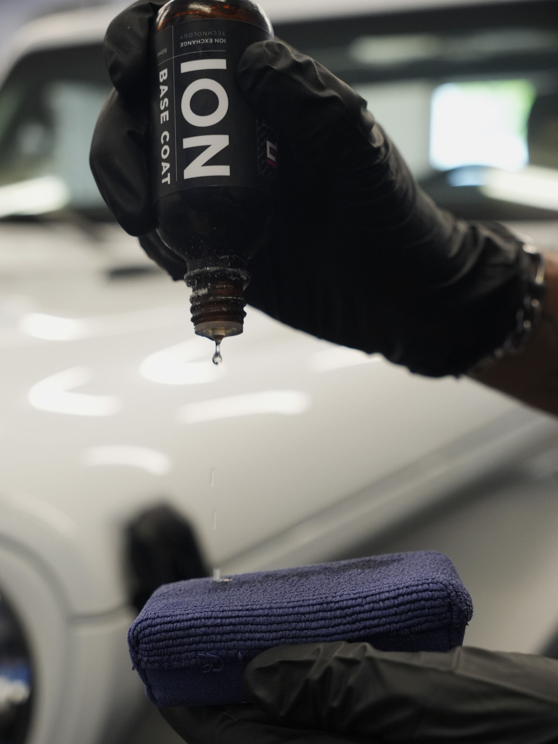 A person wearing black gloves is holding a bottle that says ion on it