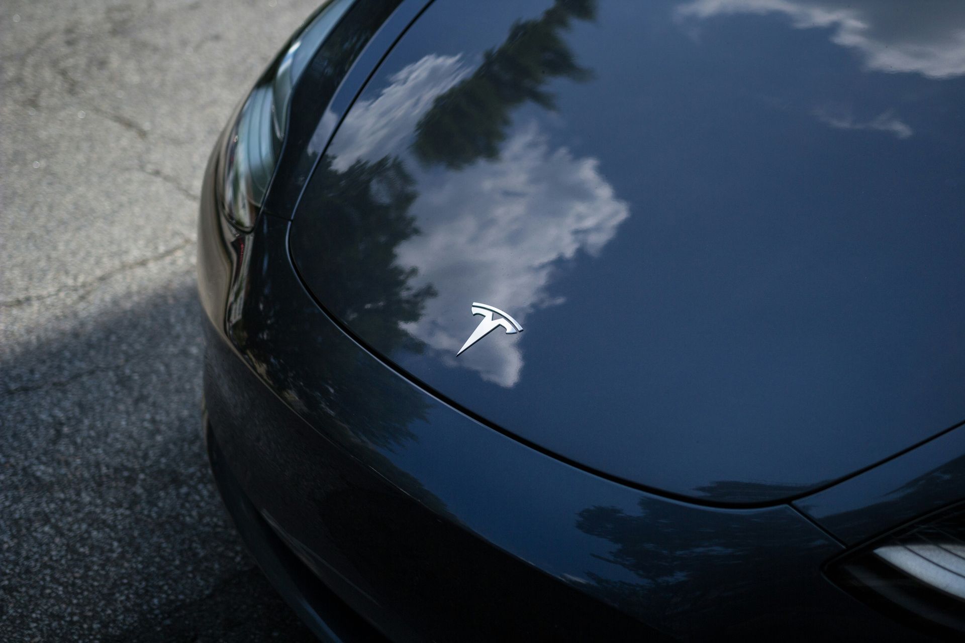 A black tesla model 3 is parked on the side of the road.