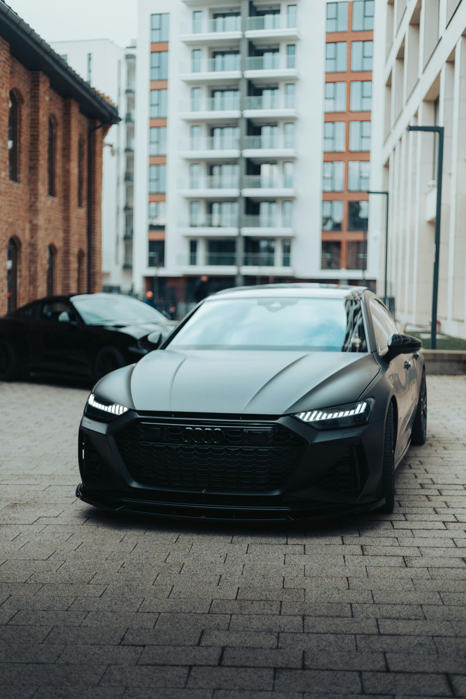 A black car is parked in front of a building.