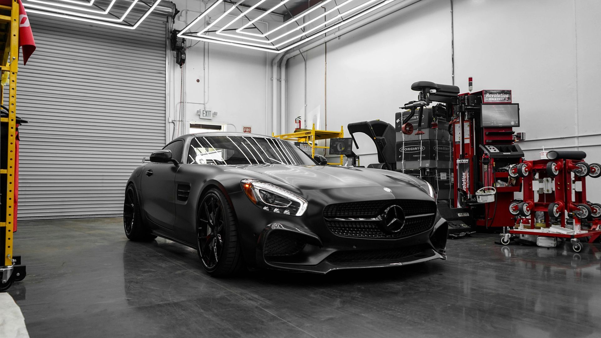 A black mercedes amg gt is parked in a garage.