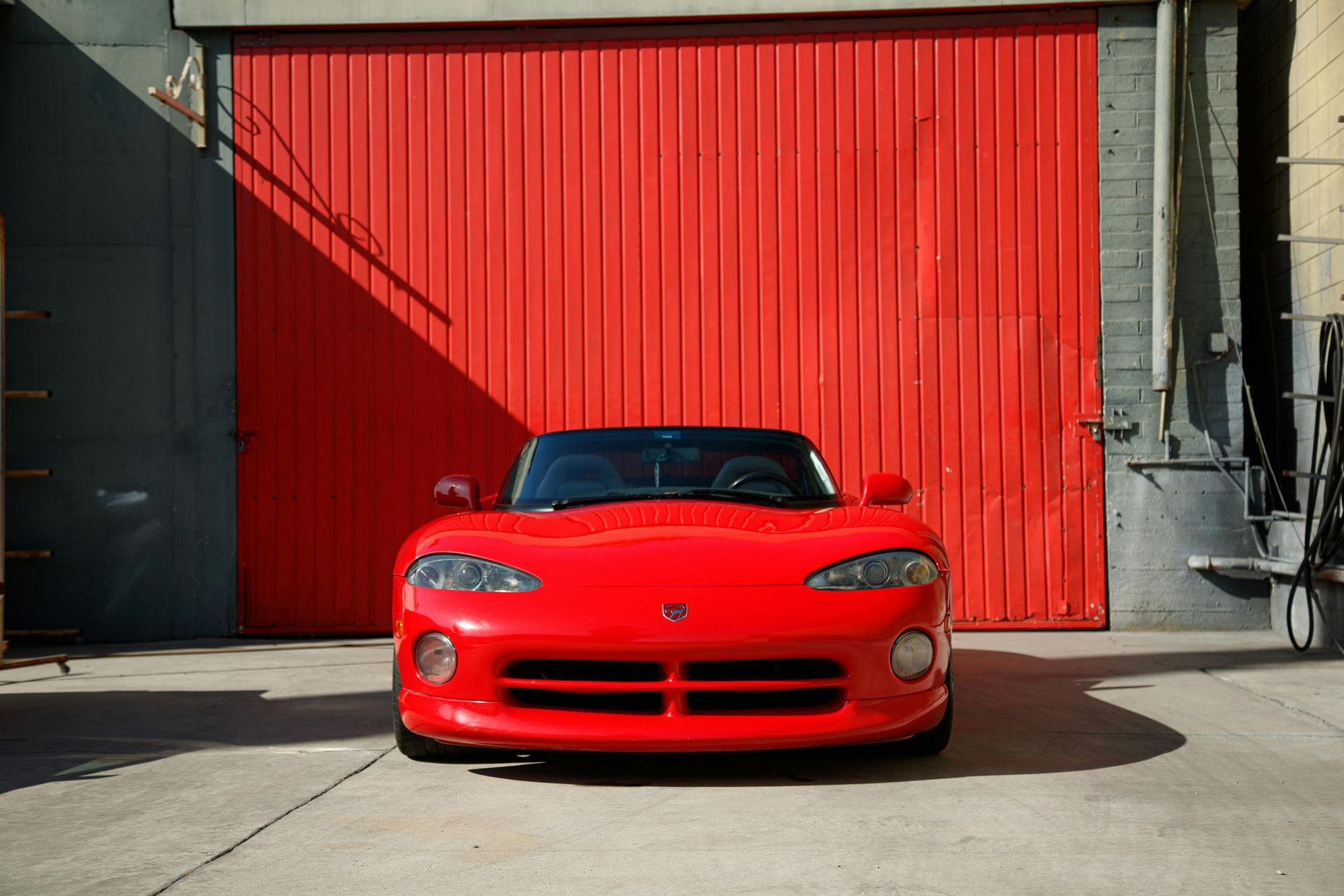 Red Dodge Viper sports car parked in front of a red garage door.