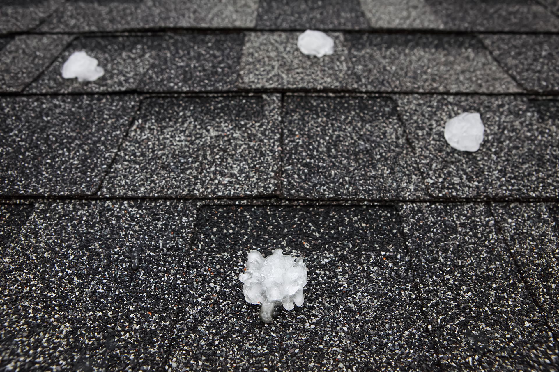Hail on a dark gray asphalt shingle roof.