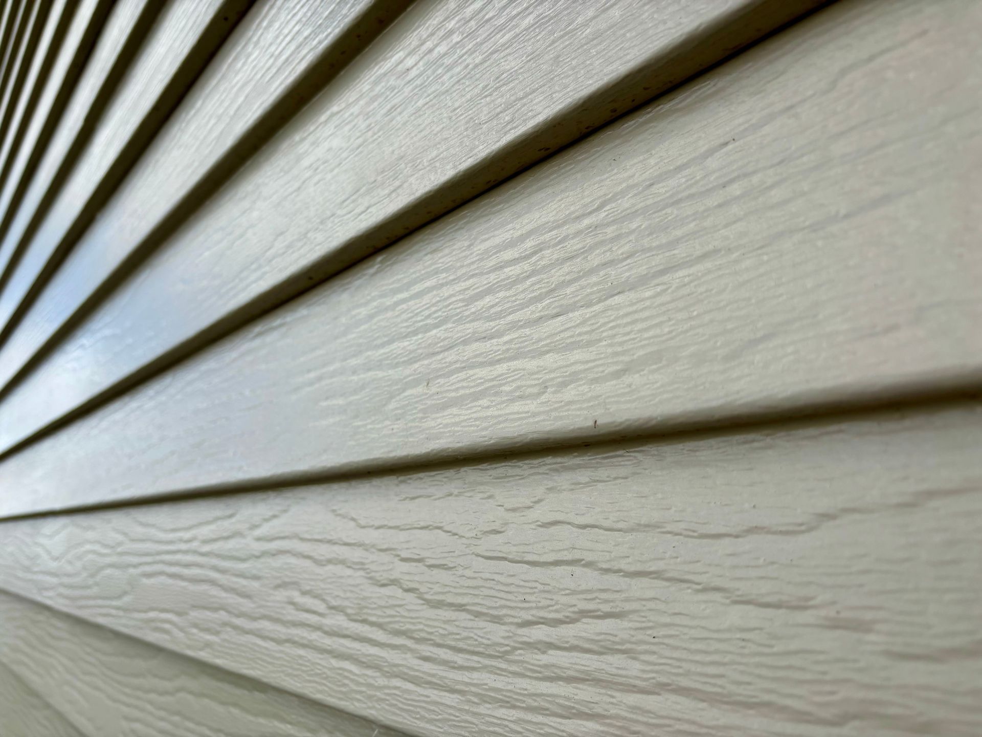 Close-up of beige horizontal siding with wood grain texture.