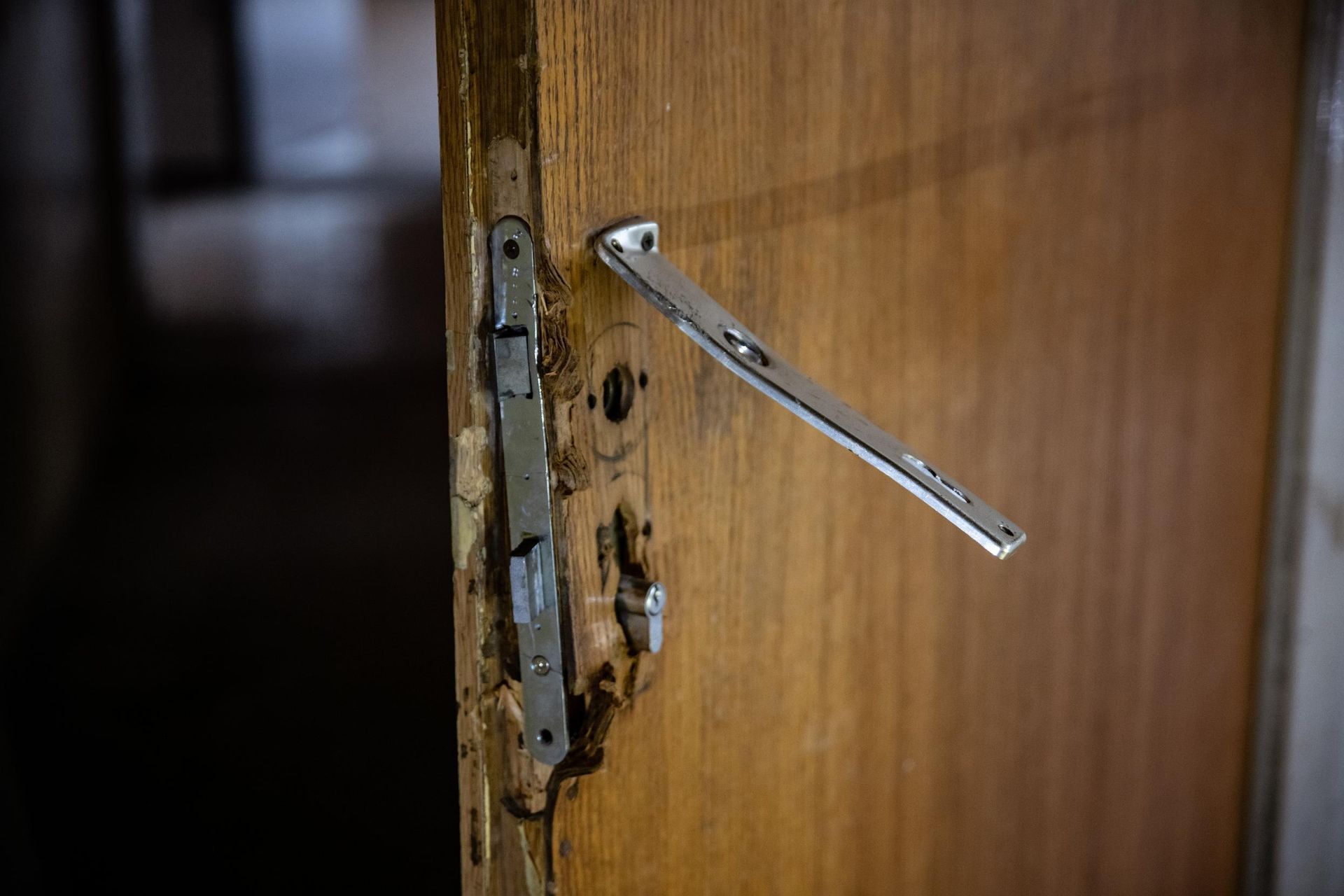 Damaged wooden door with broken metal door handle.
