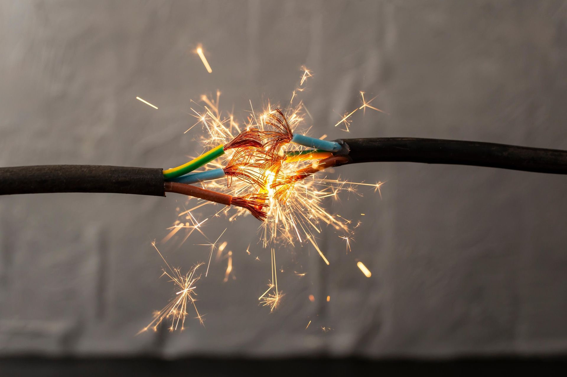 Damaged electrical wires sparking with exposed colored wires.