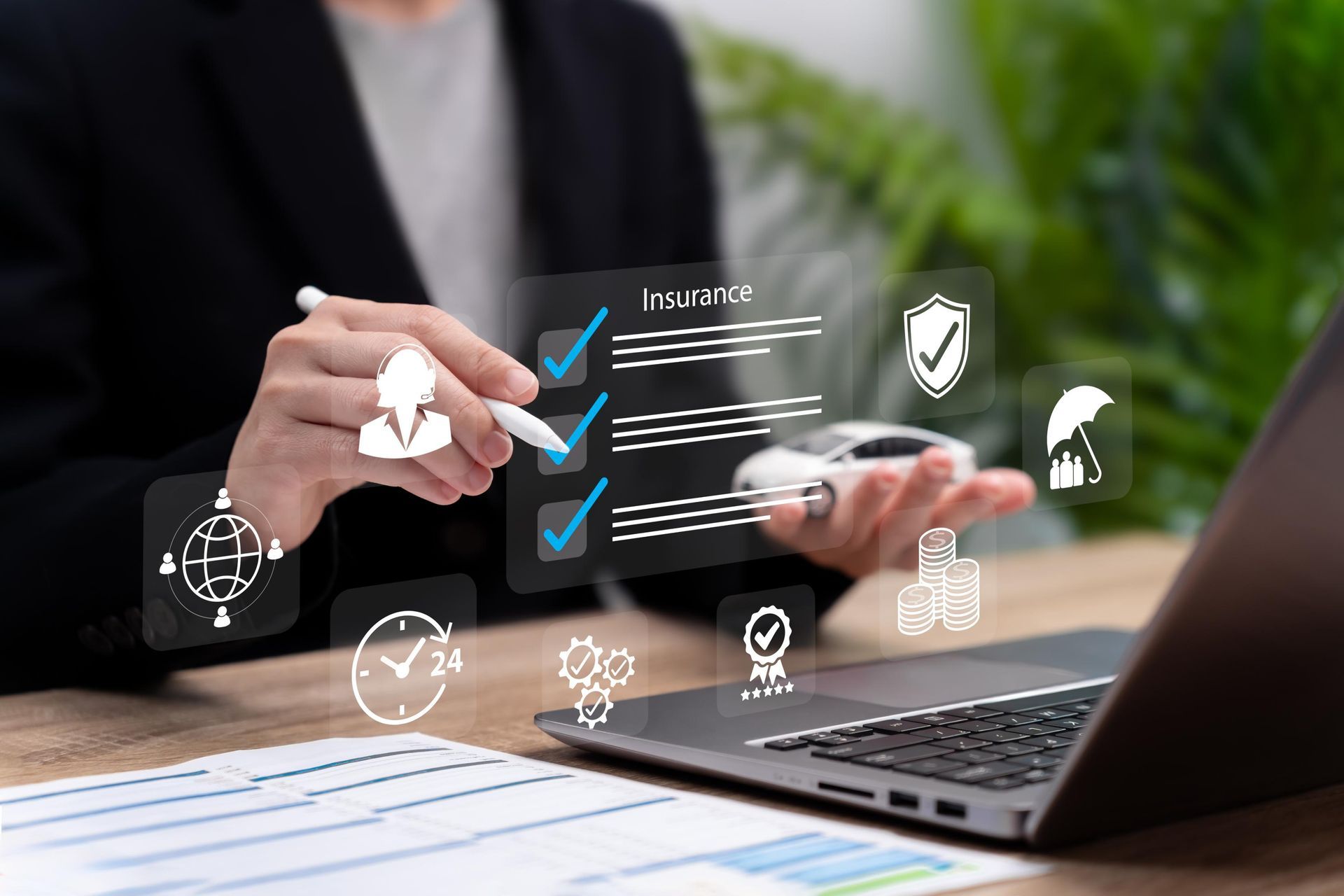 Person holding a pen, interacting with an overlaid checklist and car icons near a laptop, possibly reviewing insurance.