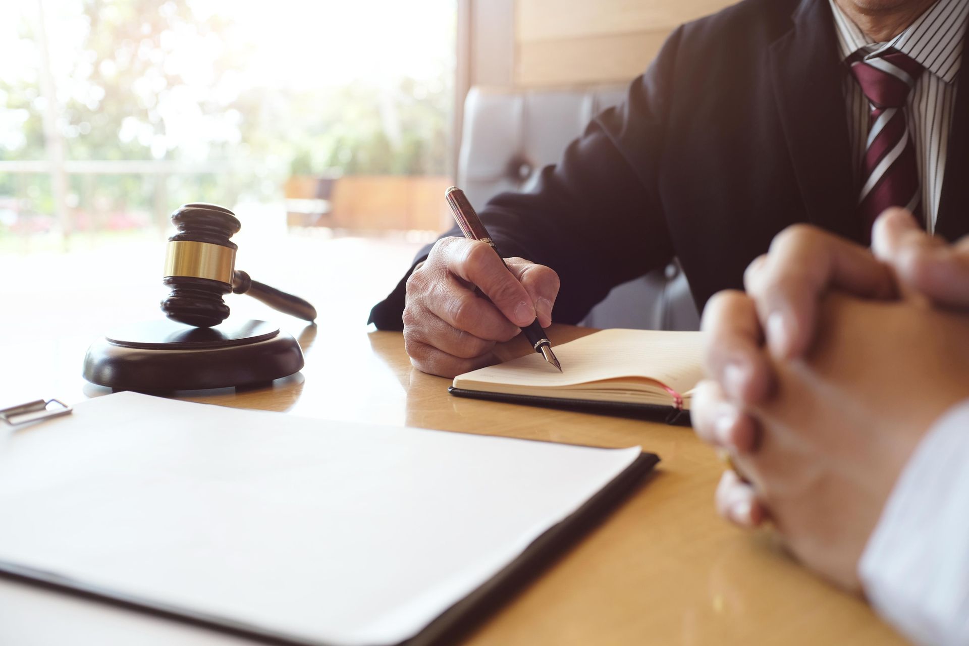 Lawyer taking notes during a meeting. Gavel and legal documents on the table.