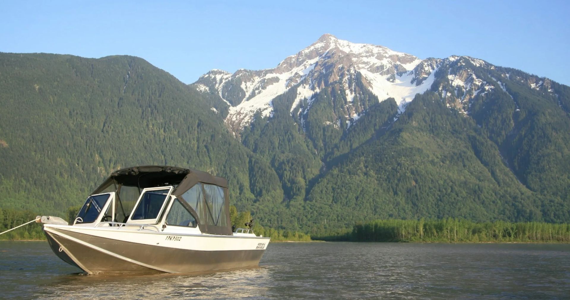 A boat is floating on a lake with mountains in the background