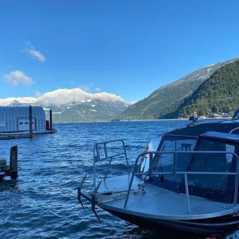 A boat is docked in the water with mountains in the background.