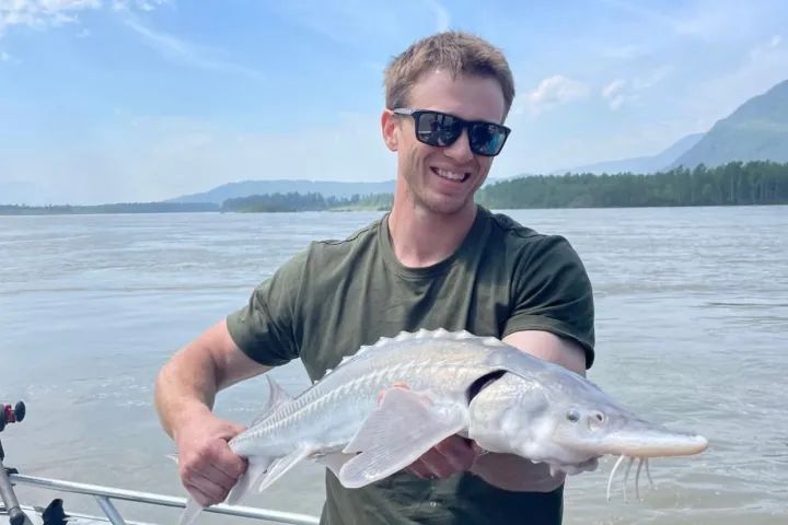 A man is holding a large fish in his hands on a boat.