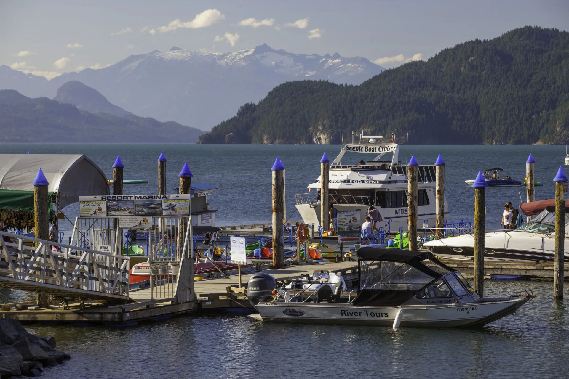 Boats are docked at a dock with mountains in the background