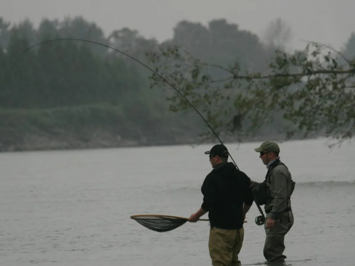 Two men are fishing in the water and one is holding a net