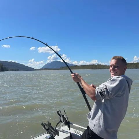 A man is fishing on a boat in the water.