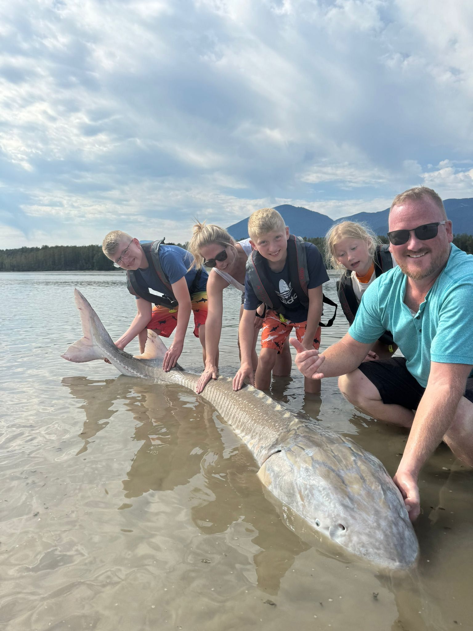 family with sturgeon in shallow water
