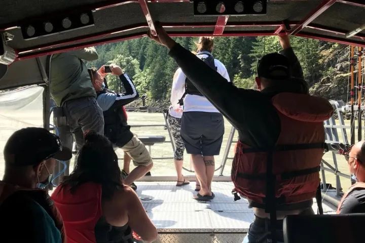 A group of people are sitting on a boat looking out over a river.