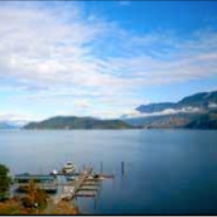A large body of water with mountains in the background and a dock in the foreground.