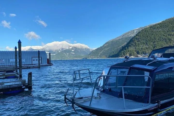 A boat is docked at a dock in the water with mountains in the background.