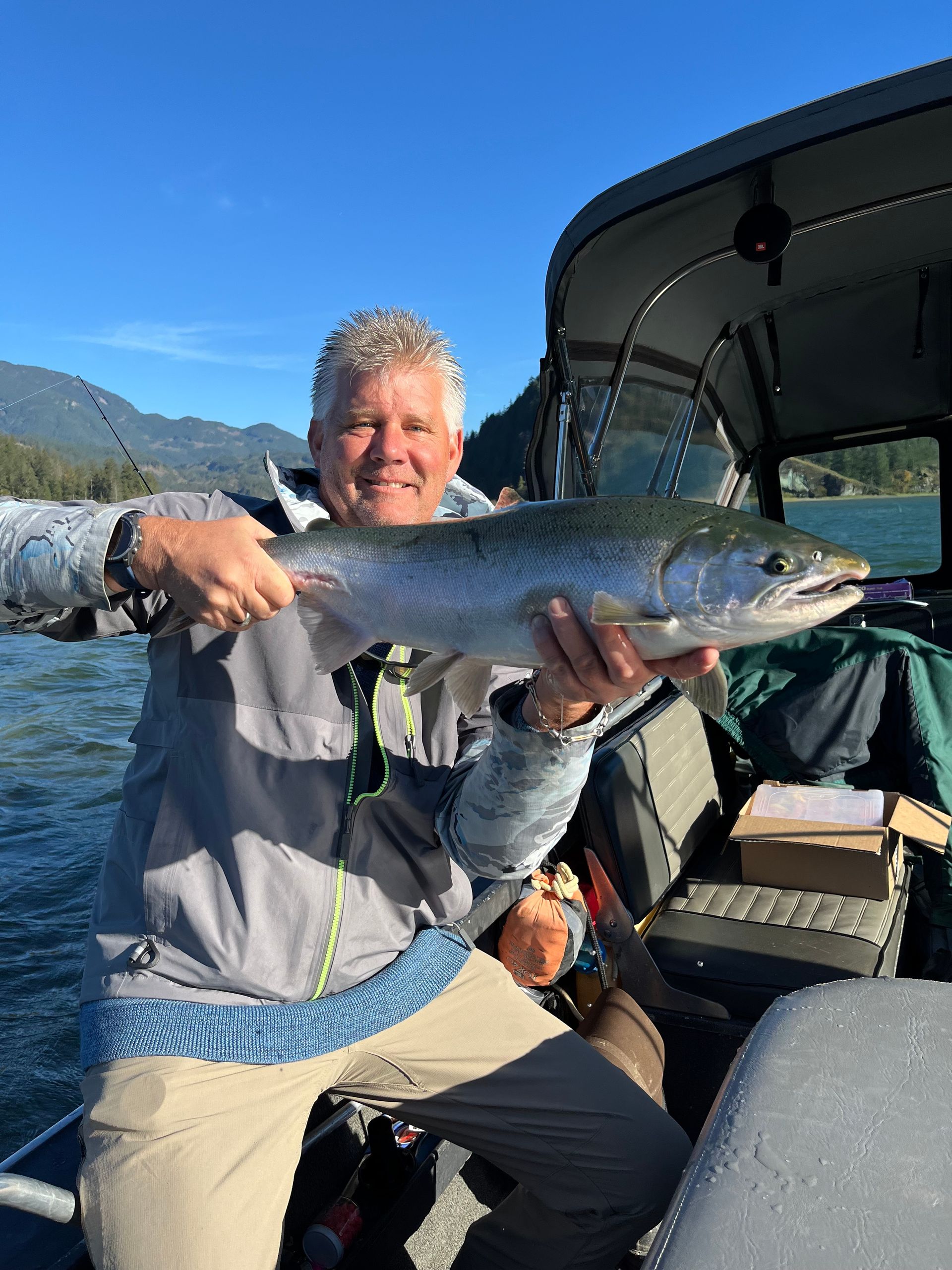 A man is holding a large fish in his hands in front of a boat.