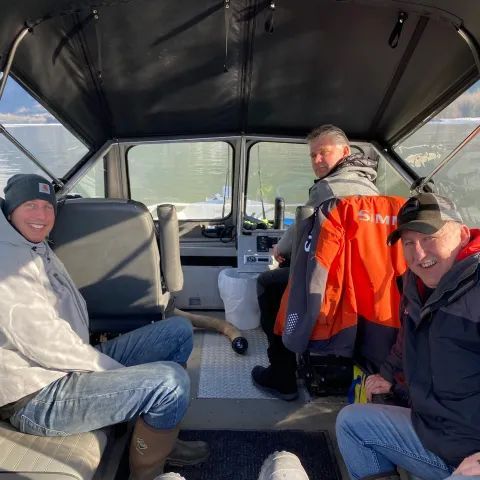A group of men are sitting in the back seat of a boat.
