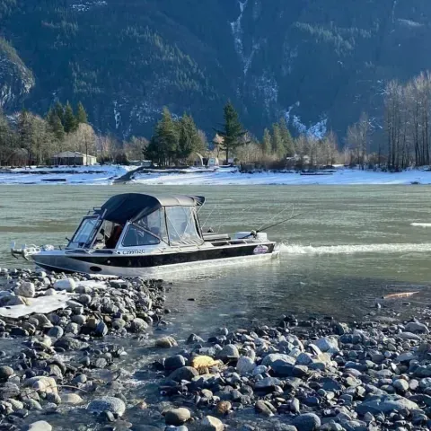 A boat is going down a river with mountains in the background.