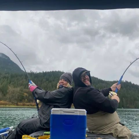 A man and a woman are fishing on a boat.