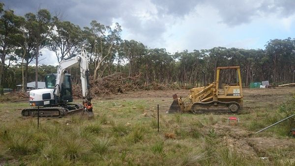 A bulldozer and an excavator are sitting in a field.