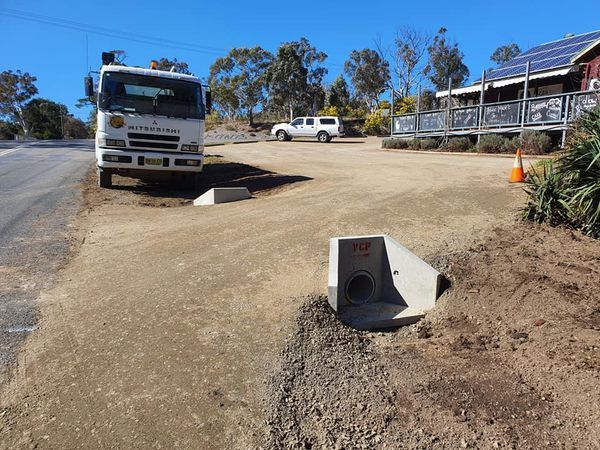A white truck is parked in a dirt lot next to a house.