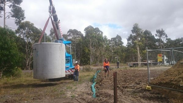 A large pipe is being lifted by a crane in a field.