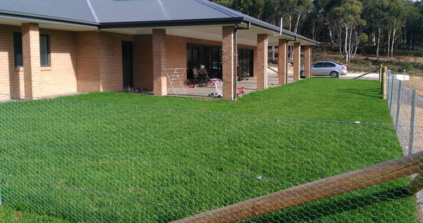 A large brick house with a large lawn in front of it.
