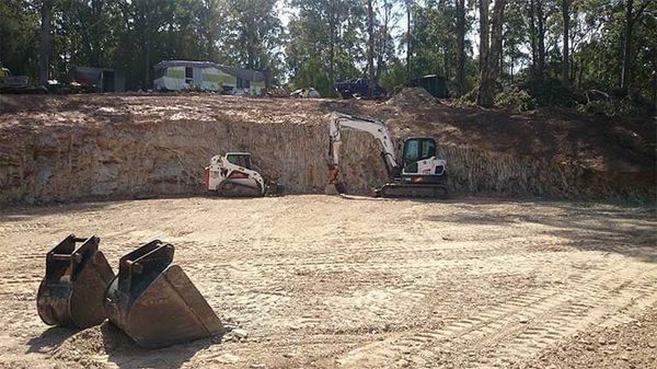 A couple of buckets sitting on top of a dirt field.