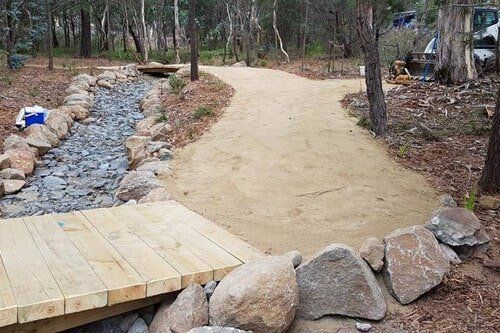 A wooden bridge over a stream in the middle of a forest.