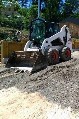 A bobcat skid steer is sitting on top of a dirt road.