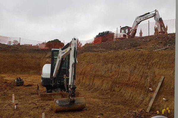 A couple of excavators are sitting in a dirt field.
