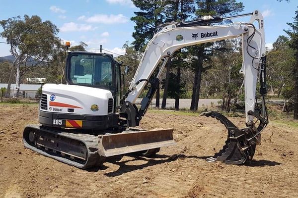 A bobcat excavator is parked in a dirt field.
